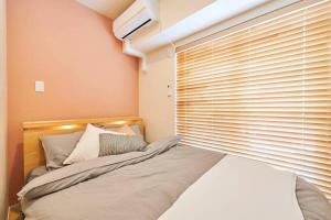 a bedroom with a bed and a window with blinds at 江戸川橋レジデンス EDOGAWABASHI RESIDENCE in Tokyo