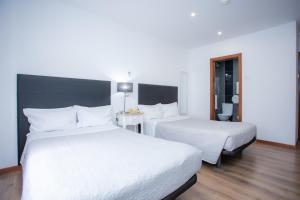 a hotel room with two beds with white sheets at Hotel Domus in Coimbra