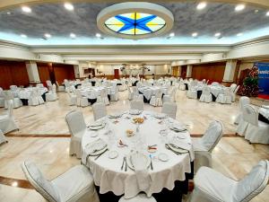 um grande salão de banquetes com mesas e cadeiras brancas em Hotel Santa Cecilia em Ciudad Real