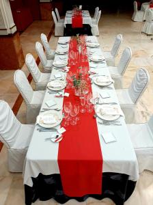 una mesa larga con sillas blancas y mantel rojo y blanco en Hotel Santa Cecilia, en Ciudad Real
