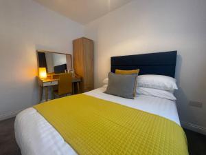 a bedroom with a yellow and white bed and a desk at Modern & cozy 2 bed bungalow in Horden