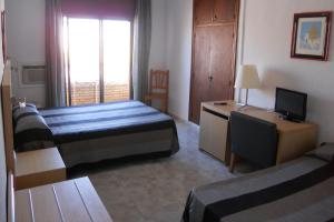 Una habitación de hotel con dos camas, un escritorio y un televisor. en Hotel Sacratif, en Torrenueva 37 fotos más