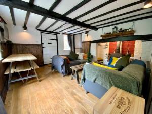 ein Wohnzimmer mit einem Sofa und einem Tisch in der Unterkunft Beautiful 500 year old listed Kentish cottage in Wingham