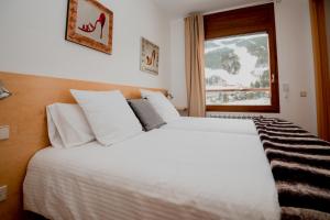 um quarto com uma grande cama branca e uma janela em Sol Tarter 4-7 em El Tarter