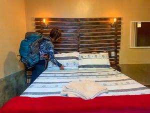 una mujer poniendo almohadas en una cama en una habitación en Pousada Aconchego - Suítes Rústicas e Privativas, en Lençóis