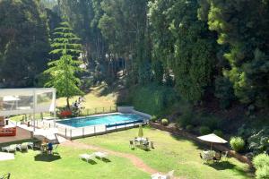 a swimming pool in a yard with tables and chairs at Hotel Bosque de Reñaca in Viña del Mar