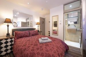 a bedroom with a red bed and a bathroom at Cornerways Guest House in St Ives