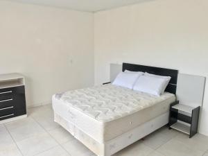 1 dormitorio blanco con 1 cama grande y paredes blancas en Residêncial Casa da Vila apto 1, en Imbituba