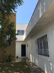 Residêncial Casa da Vila apto 1 في إيمبيتوبا: مبنى ابيض وفيه بوابه جانبيه