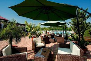 un patio con tavoli, sedie e ombrellone di Hotel Levisticum a Bacău