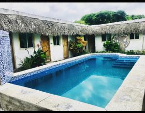 una casa con piscina di fronte a un edificio di Hostal San Andrés de k-noa a Canoa