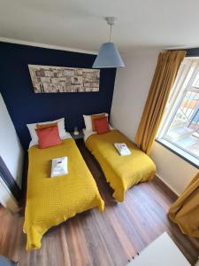 a room with two beds with yellow sheets and a window at ENTIRE Lovely Scottish Cottage in Selkirk