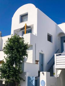 a white building with a tree in front of it at Elkaza Villas in Fira