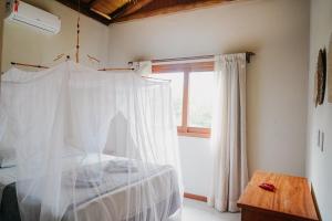 um quarto com uma cama com cortinas brancas e uma janela em Casa TRIP - 2 suítes na praia de Taipu de Fora em Taipu