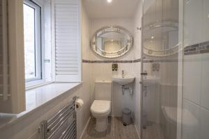 a bathroom with a toilet and a sink and a mirror at Cornerways Guest House in St Ives