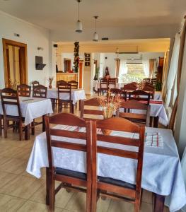 a dining room with tables and chairs with white table cloth at Pensiunea La Bunica in Rugineşti
