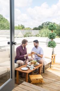 two men sitting on a patio eating food on a table at Guesthouse Charleston EAST 46 F in Charleston