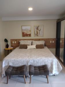 ein Schlafzimmer mit einem großen Bett mit 2 Stühlen in der Unterkunft Flat do Barão Tabatinga in Conde