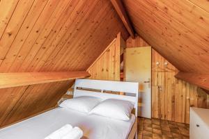 Cama en habitación con paredes y techos de madera en Calm chalet close to Cabourg center - Welkeys, en Cabourg