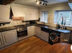 uma cozinha com armários brancos e uma máquina de lavar louça em Beautiful Cosy Townhouse 3 Double beds 2 Bathroom FREE PARKING em Kendal