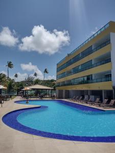 a swimming pool in front of a building at Flat do Barão Tabatinga in Conde