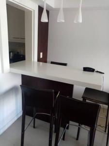 cocina con encimera blanca y sillas negras en Moderno Apartamento en la Península, en Punta del Este