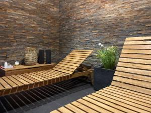 two wooden benches sitting next to a brick wall at Apartamenty Hucuł in Brenna