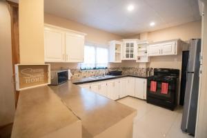 a kitchen with white cabinets and a black refrigerator at Stacys Place #1 2 Bedroom Apartment in Port-of-Spain