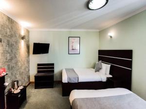 a hotel room with two beds and a tv at Epsilon Hotel in London
