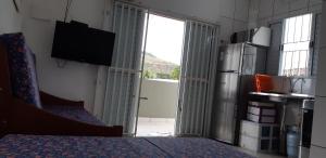 Zimmer mit einem Kühlschrank und einer Glasschiebetür in der Unterkunft 0006.04 - Maranduba - KitNet 1º Andar - 4 Pessoas - 3 Quadras Do Mar - Piscina Coletiva - WIFI in Ubatuba