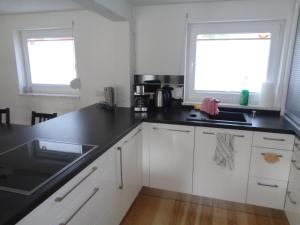 a kitchen with white cabinets and black counter tops at Ferienhaus Saremba in Joachimsthal