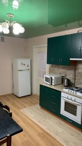una cucina con armadi verdi e frigorifero bianco di Апартаменти центр міста біля жд вокзалу Перемоги a Luc'k