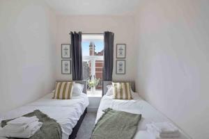 two beds in a room with a window at Town center apartment in Bishops Stortford in Birchanger