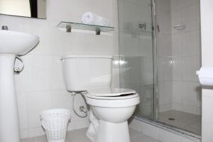 y baño blanco con aseo y ducha. en Hotel Montecarlo Boutique, en Bogotá