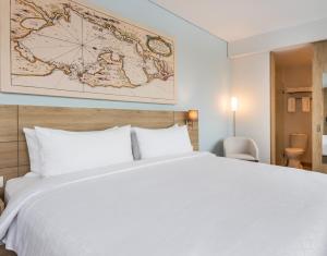 Una cama blanca en una habitación de hotel con un mapa en la pared en Holiday Inn Express Cartagena Manga, an IHG Hotel, en Cartagena de Indias