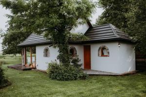 a small white house with a black roof at Domek nad stawem RODOS in Raków