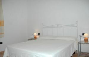 a white bedroom with a white bed with two tables at La Cinta in San Teodoro
