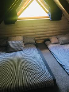 two beds in a small room with a window at Domek nad stawem RODOS in Raków