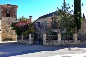 a stone building with a gate and a church at Casa Florentino Casa centenaria in Torre Val de San Pedro