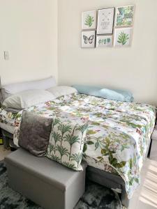 a bedroom with a bed with a floral comforter at Hola! Condotel @ Inspiria Davao in Davao City +34 photos