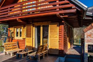 a wooden cabin with two benches on the porch at Petit chalet Belosevic in Kuželj