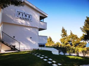 un edificio blanco con un cartel en el costado en Pine Resort, en Polychrono