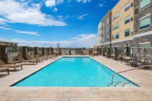 a swimming pool on a patio with chairs and a building at Hyatt House Carlsbad in Carlsbad