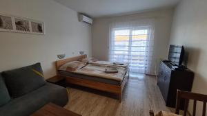 ein kleines Zimmer mit einem Bett und einem Sofa in der Unterkunft Apartmán Norika in Podhájska