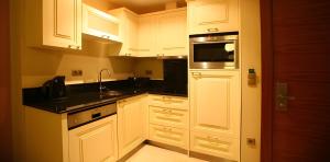 cocina con armarios blancos y microondas en Apartments Goldcity 2+1, en Kargicak