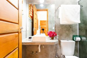 een badkamer met een wastafel, een toilet en een spiegel bij UNKUÉ POUSADA FLATS in Jericoacoara