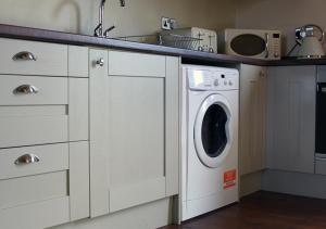 una cocina con lavadora bajo una barra en Hidden gem apartment in sleepy Durham village., en Cornsay