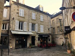 un grupo de edificios con mesas y sillas en una calle en Charming one bedroom apartment in Brive center, en Brive-la-Gaillarde