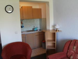 une petite cuisine avec un évier et un fauteuil rouge dans l'établissement Mod Apartment in Rerik Germany with Terrace, à Rerik