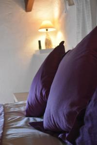 a bed with purple pillows and a lamp on it at Casa KiSi Cottage, Rural Boutique Bed & Breakfast in Málaga
